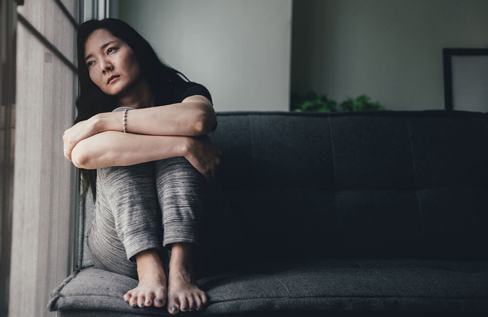 young woman sitting on couch depressed and emotional