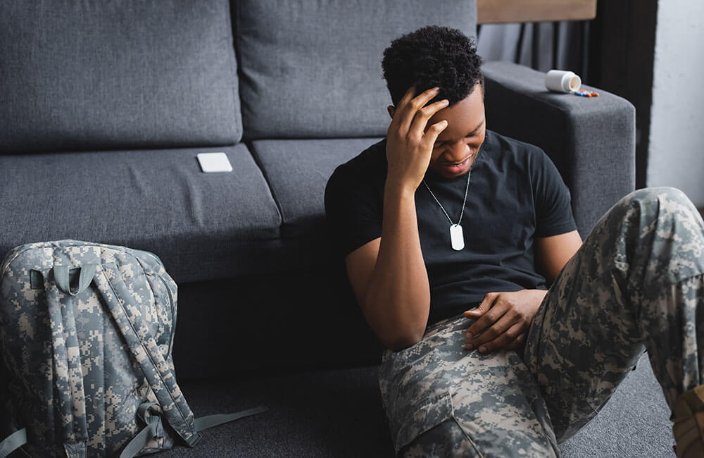 stressed african american soldier with army badge suffering from PTSD at home