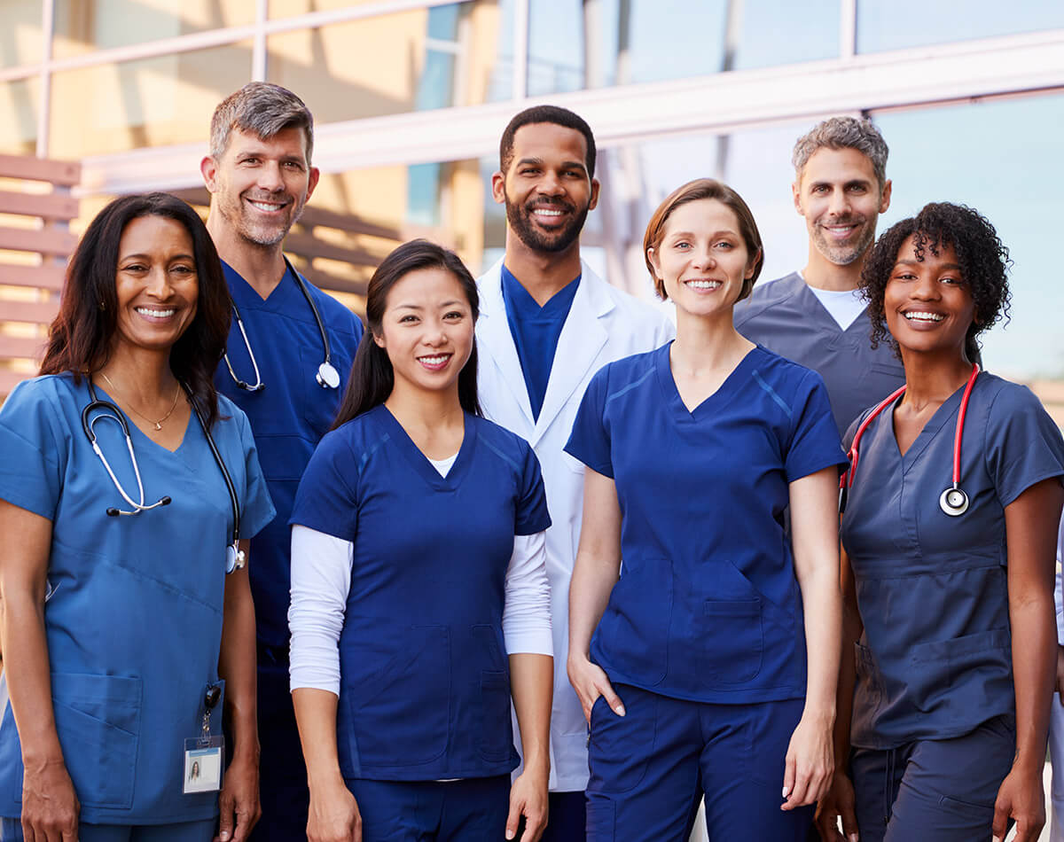 Smiling medical team standing together outside a hospital
